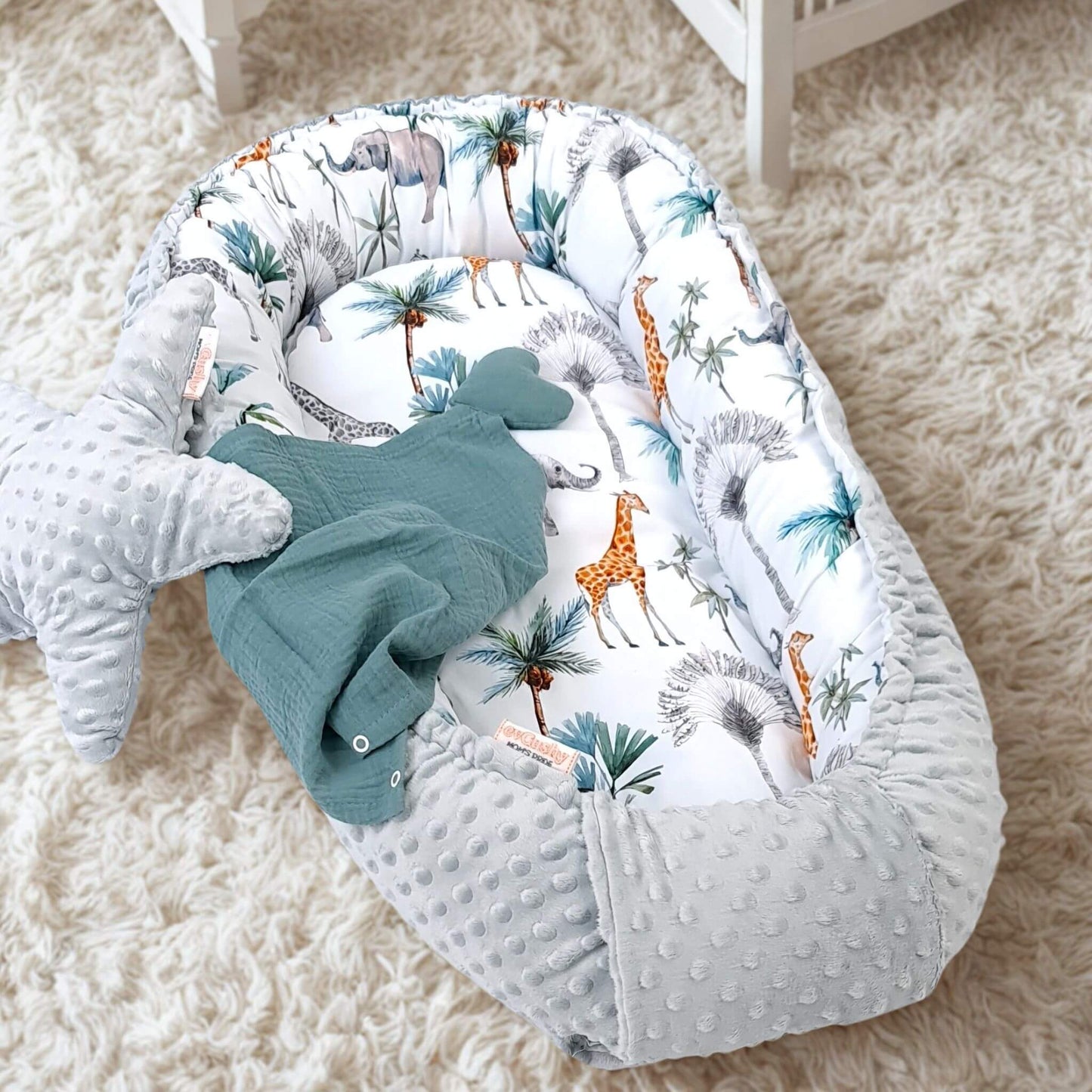 baby nest for newborn grey plush minki fabric and 100% cotton safari jungle animals pattern lying on the floor in baby nursery