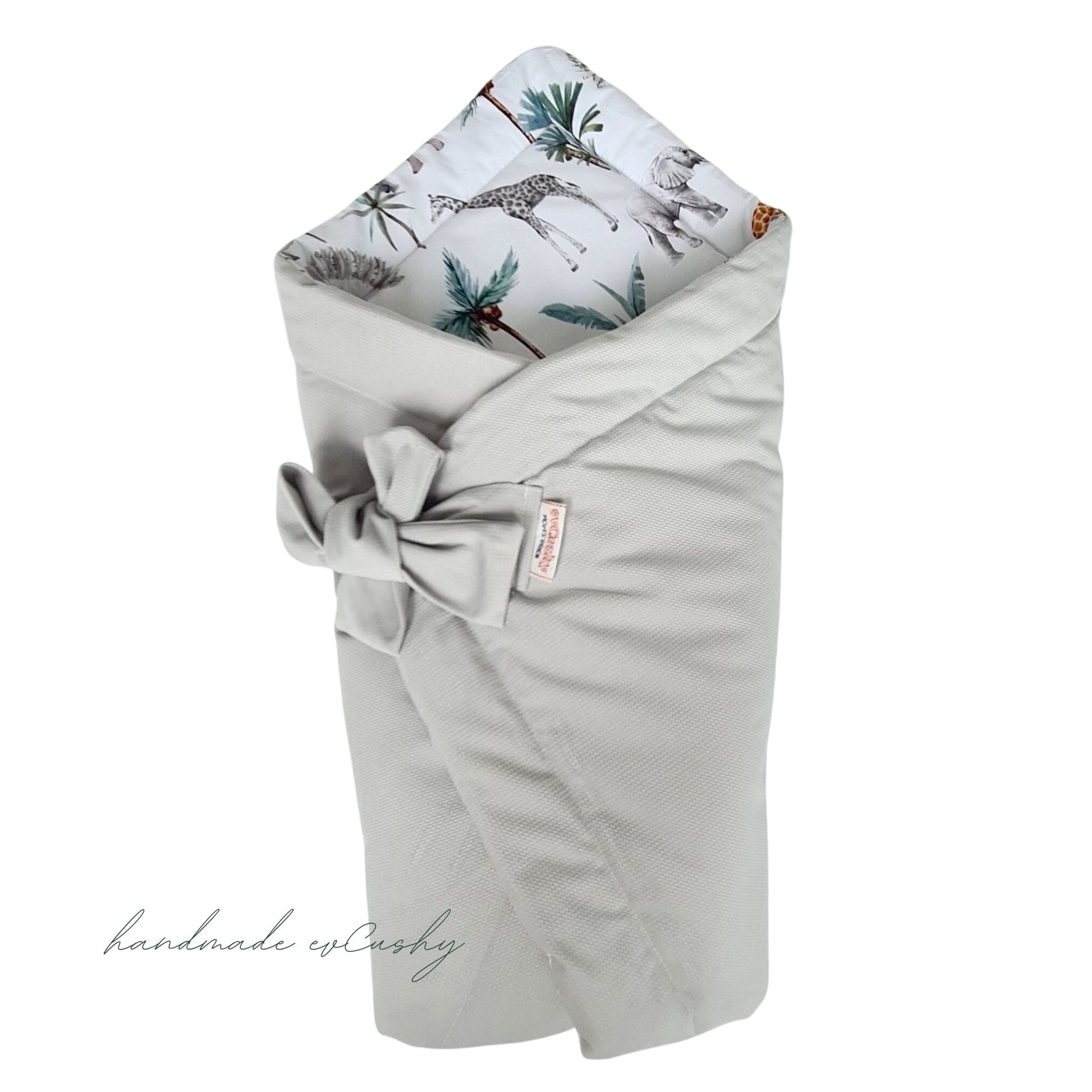 multi-functional 3-in-1 swaddle blanket, featuring a stylish grey exterior and a delightful safari animal pattern on the inside. It is elegantly tied with a bow for added charm.