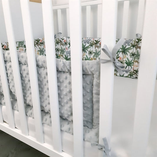 White crib with gray and green floral bumper pads