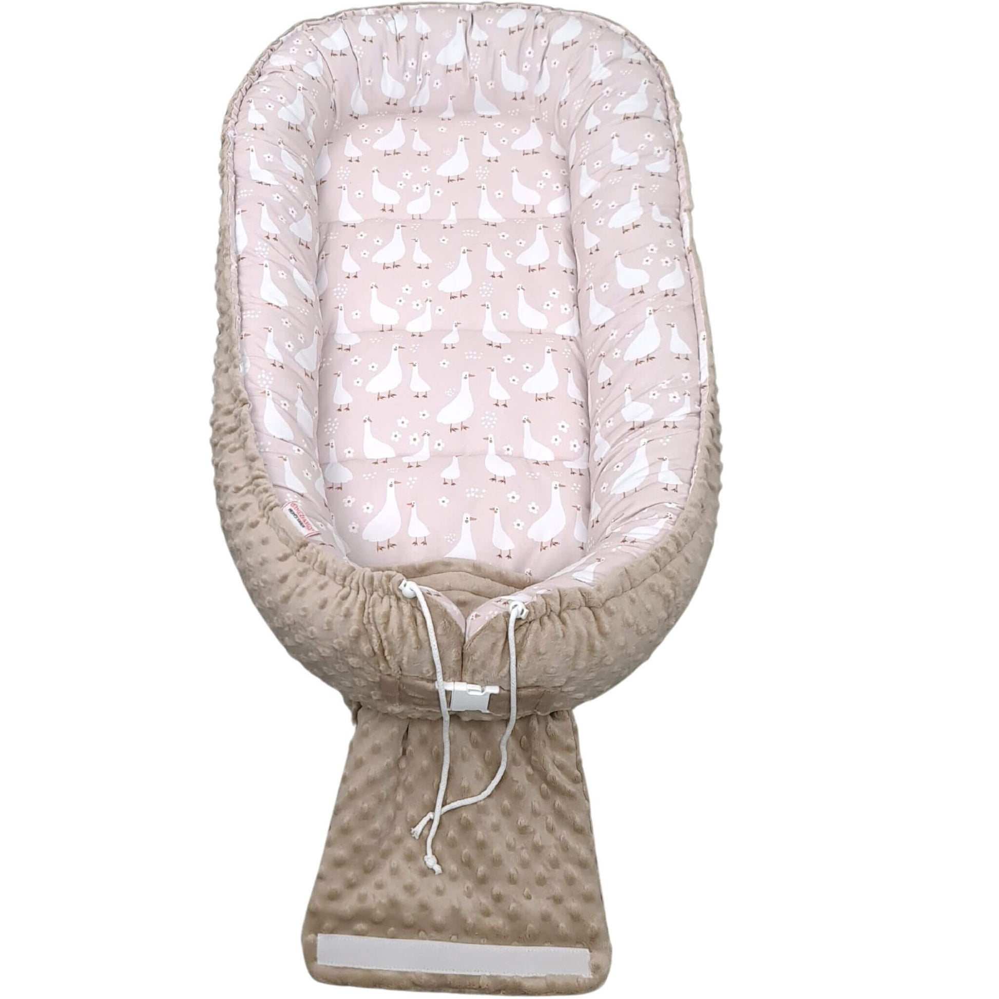 Baby nest with pink and white patterned top and beige bottom on a white background