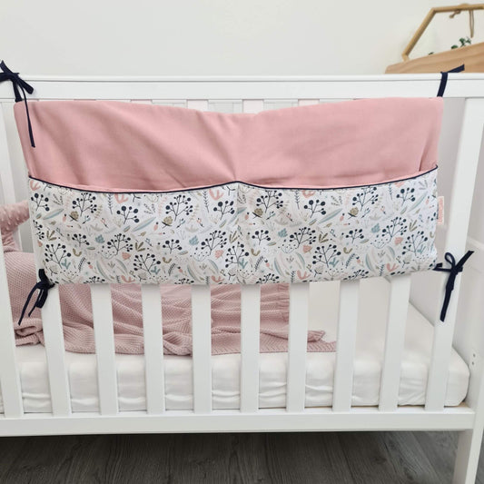 Crib with pink and floral bumper organizer for baby essentials