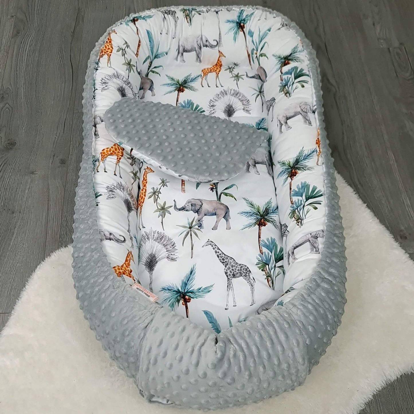 Safari pattern toddler nest with soft liner, ideal for naps and playtime.