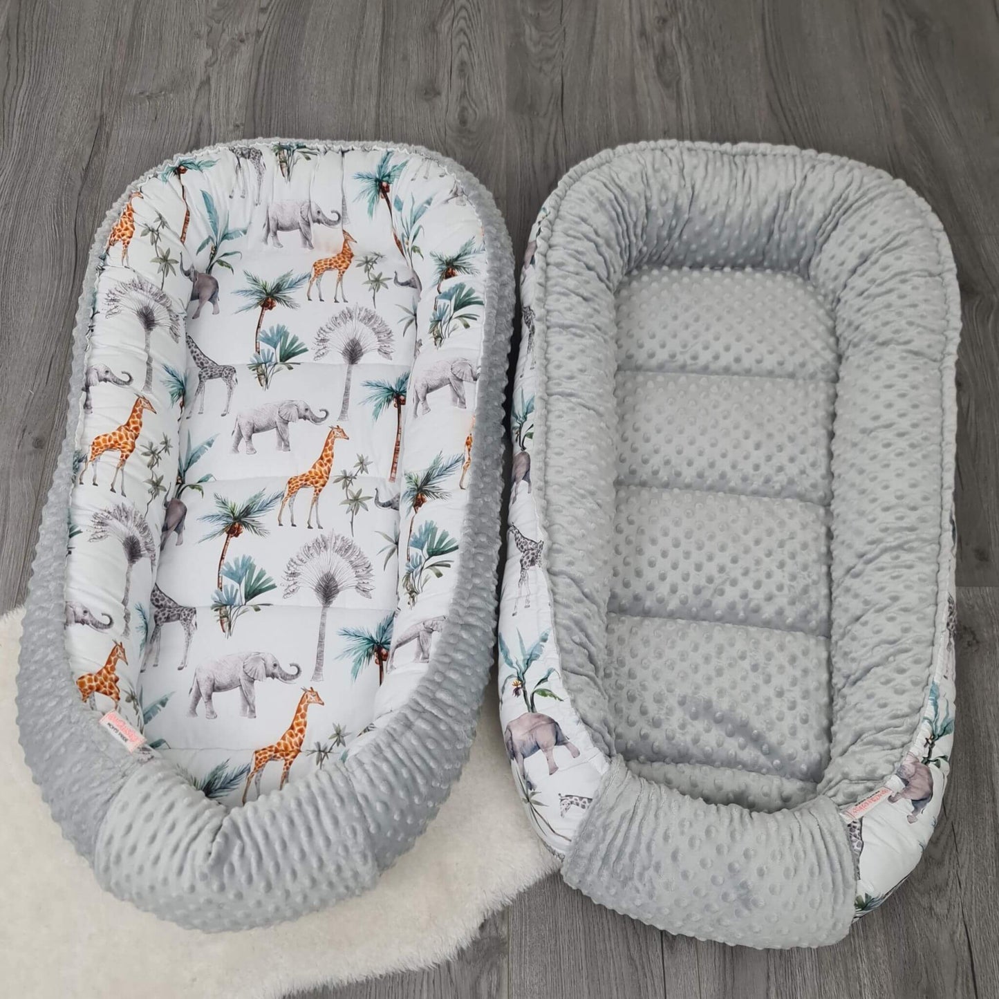 Safari themed baby nest reversible with giraffes, elephants and tropical palm leaf design.
