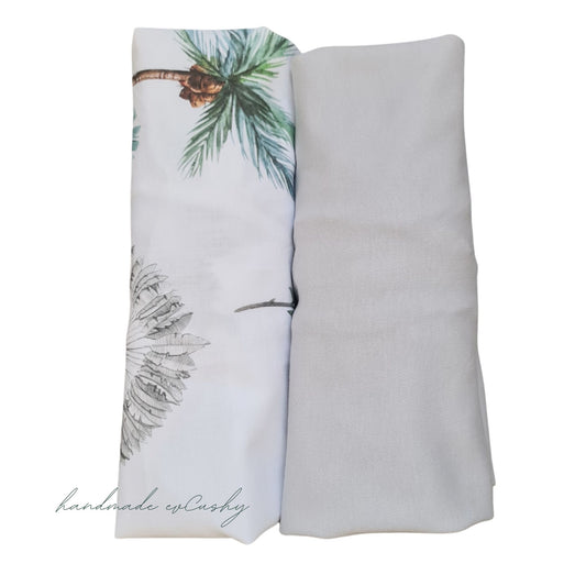 Two fitted sheets for Moses basket and carrycot - one grey and one with a safari palm tree pattern. High-quality 100% cotton for baby's comfort and style.