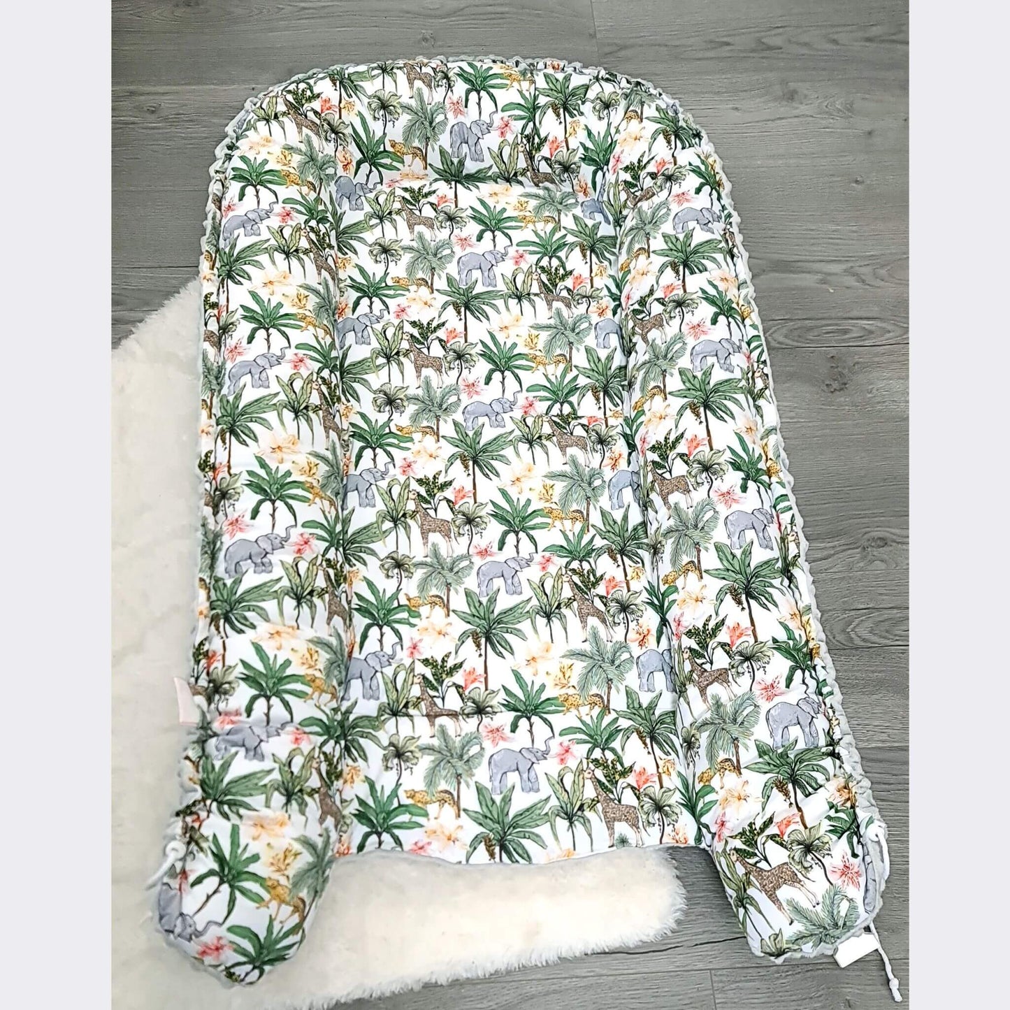 Baby changing pad with jungle animal pattern on a wooden floor