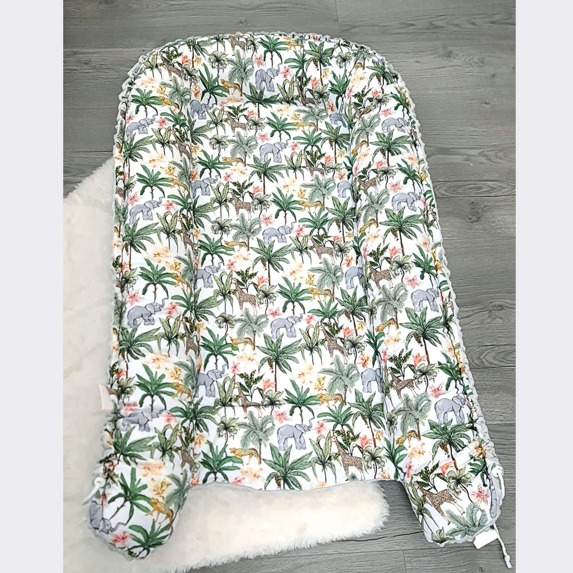 Baby changing pad with jungle animal pattern on a wooden floor