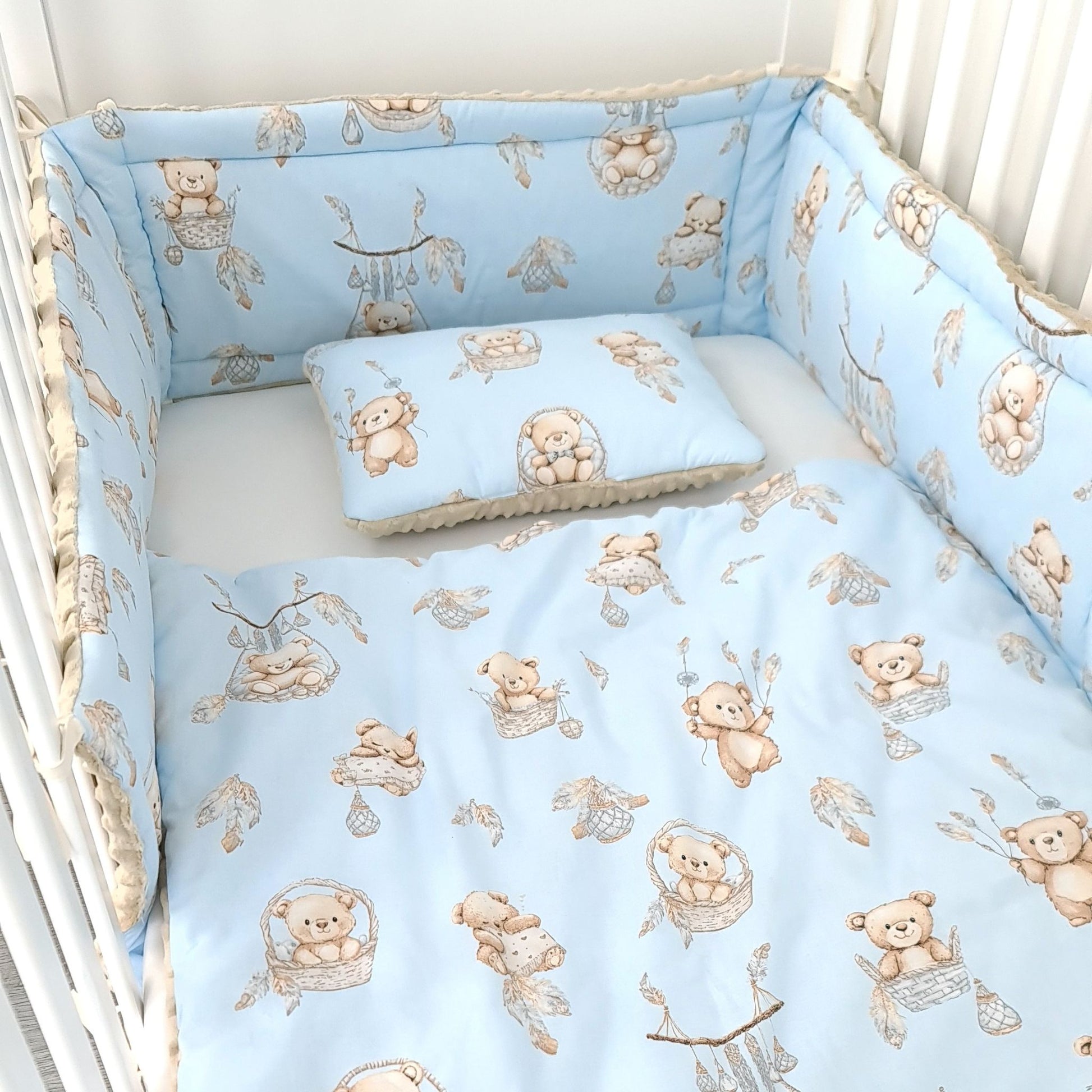 Crib set with teddy bear pattern on a light blue background, baby cot with matching nursery accessories cot bed bumper quilt and pillow in blue