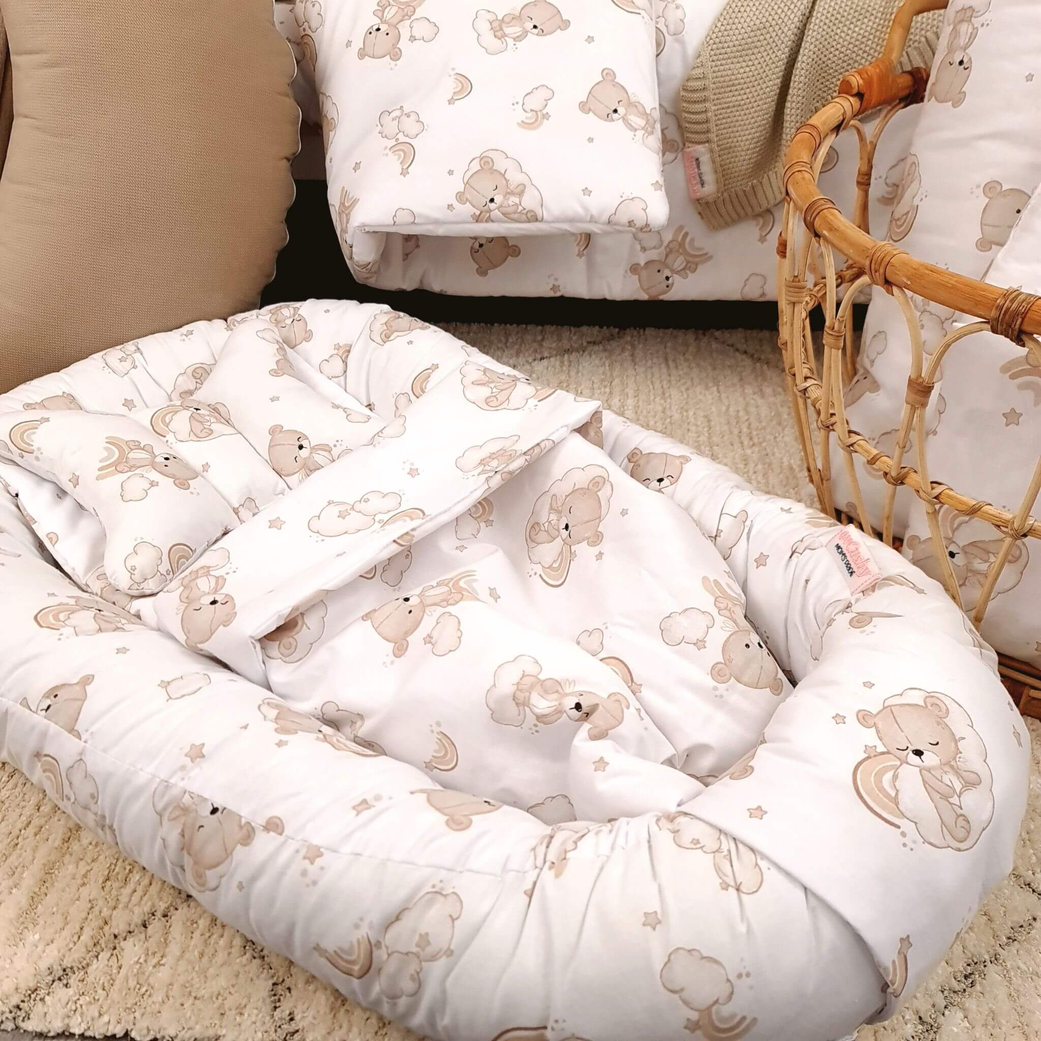 Baby crib with teddy bear patterned bedding and a wicker basket. baby sleep pod 100% cotton white and beige with teddies and rainbows