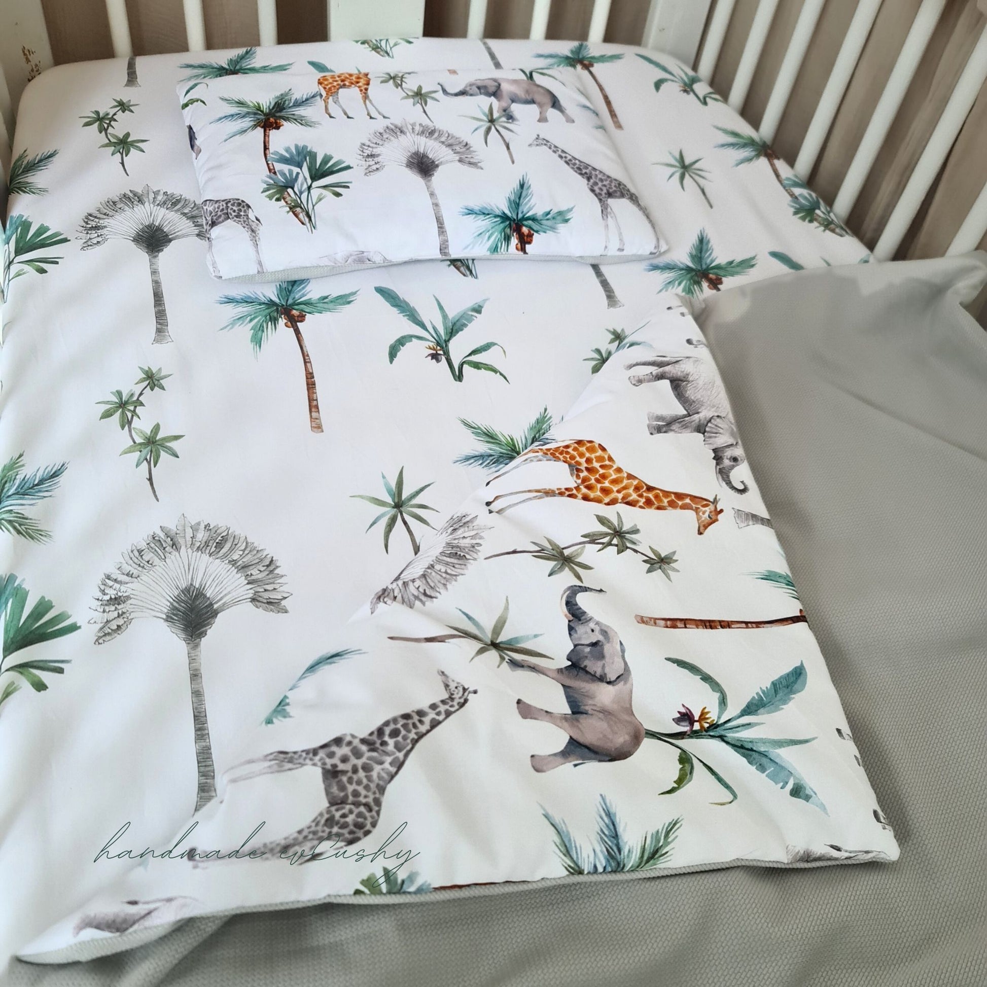 "Image of a newborn set with a charming grey and safari patterned cotton quilt and pillow, enhanced with luxuriously soft velvet for ultimate comfort." in the baby cot