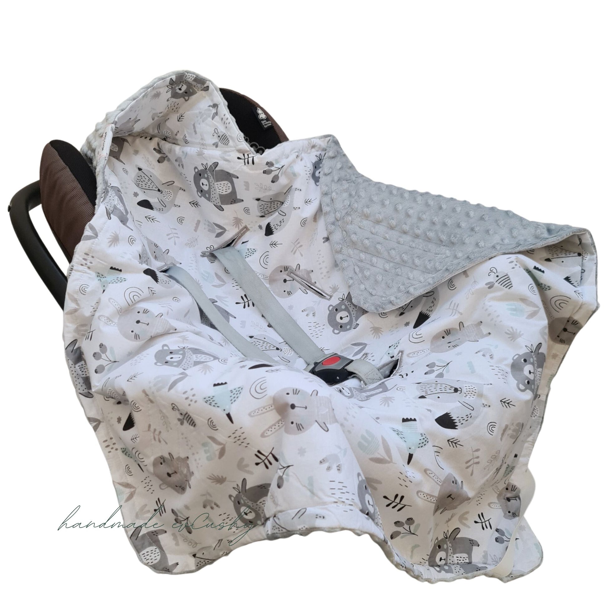 Image: A grey car seat blanket for newborns with an adorable animal pattern and a convenient hood, fastened securely with Velcro. fit 3 and 5 points harness