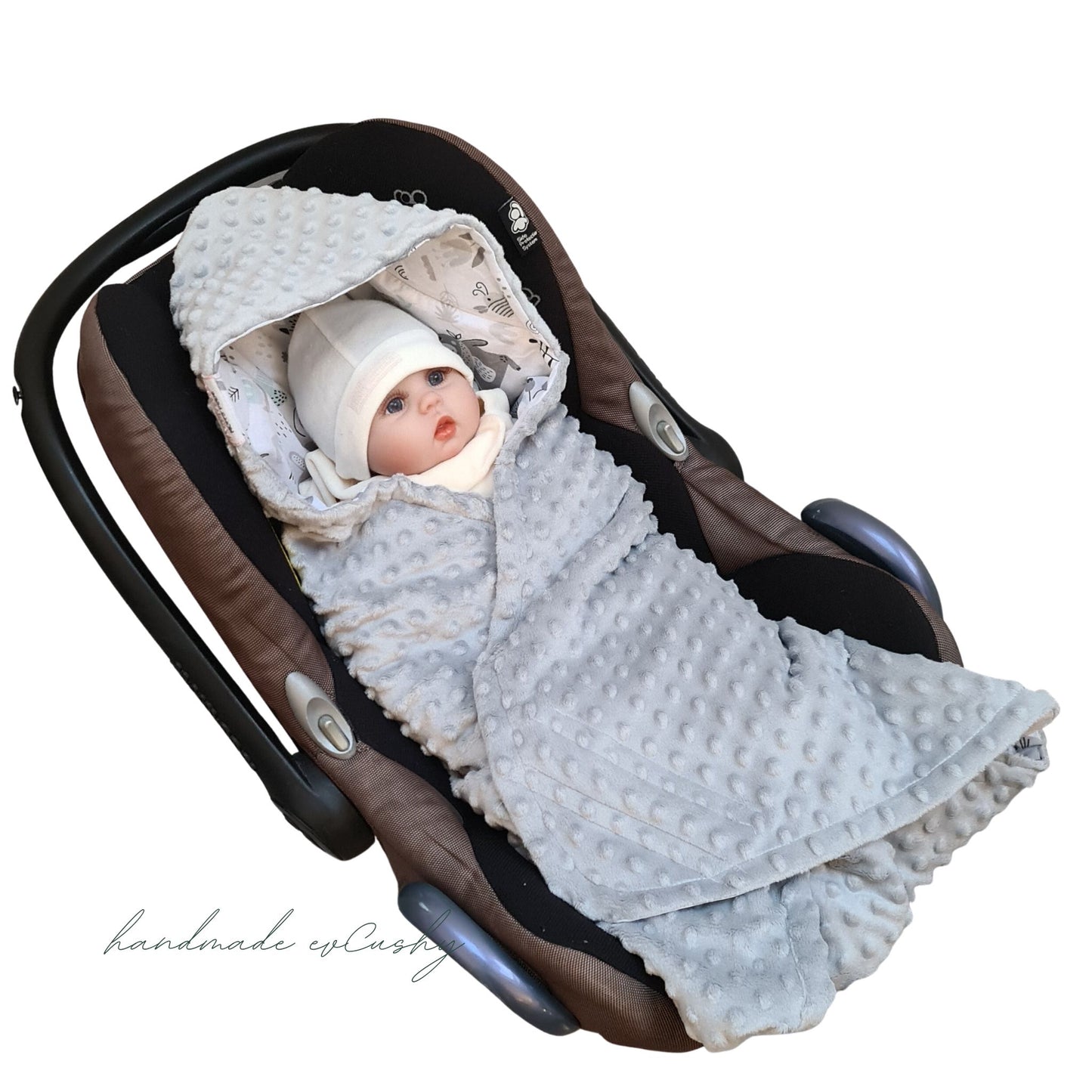 Image: A grey car seat blanket for newborns with an adorable animal pattern and a convenient hood, fastened securely with Velcro.