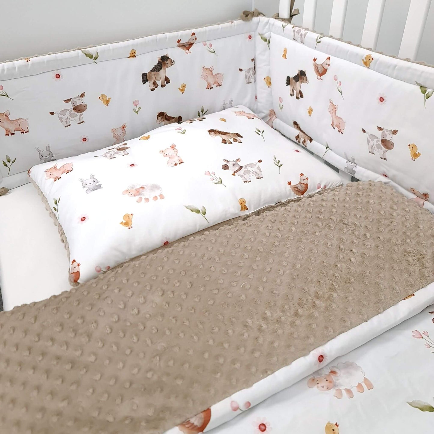 Close-up of Farm Friends quilt and pillow with ponies, cows, and bunnies and brown minky blanket and cot bed bumper for cot size 140x70cm
