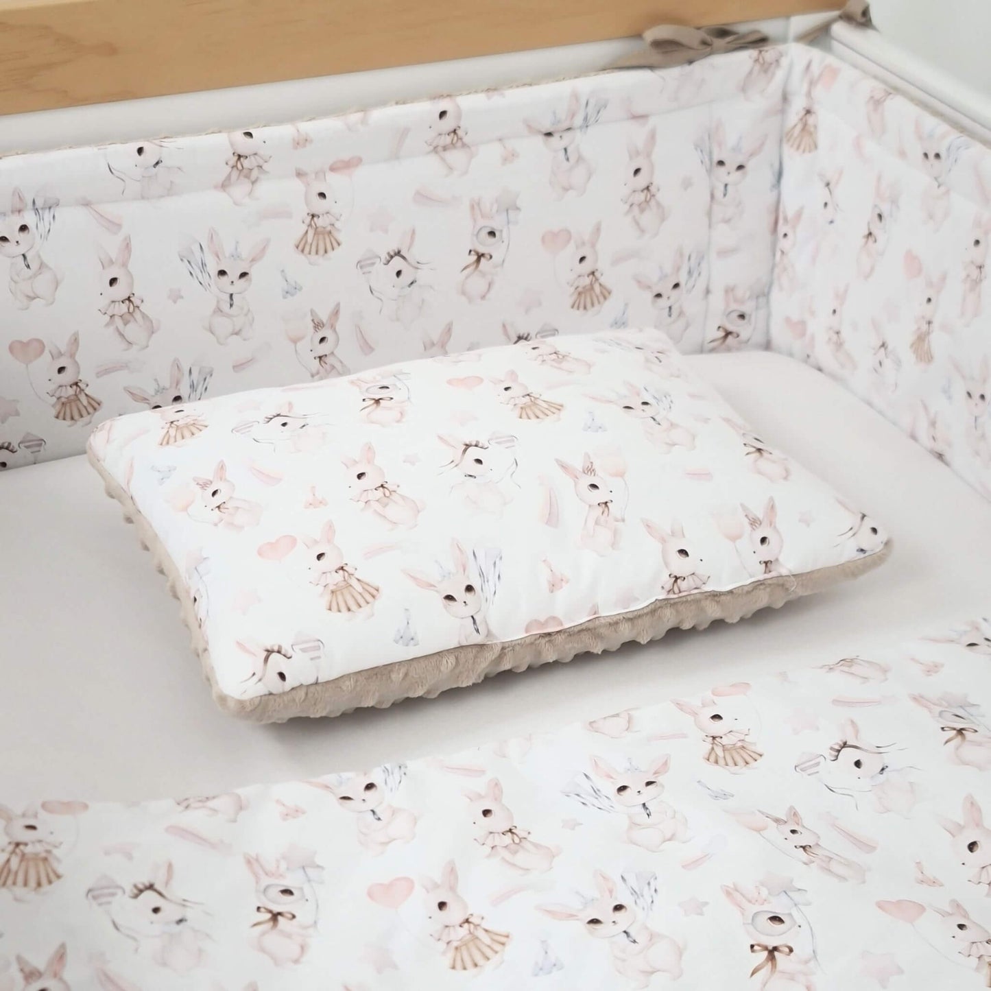 Close-up of retro bunny cotton fabric on cot  bed bumper and baby quilt and pillow in a standard crib
