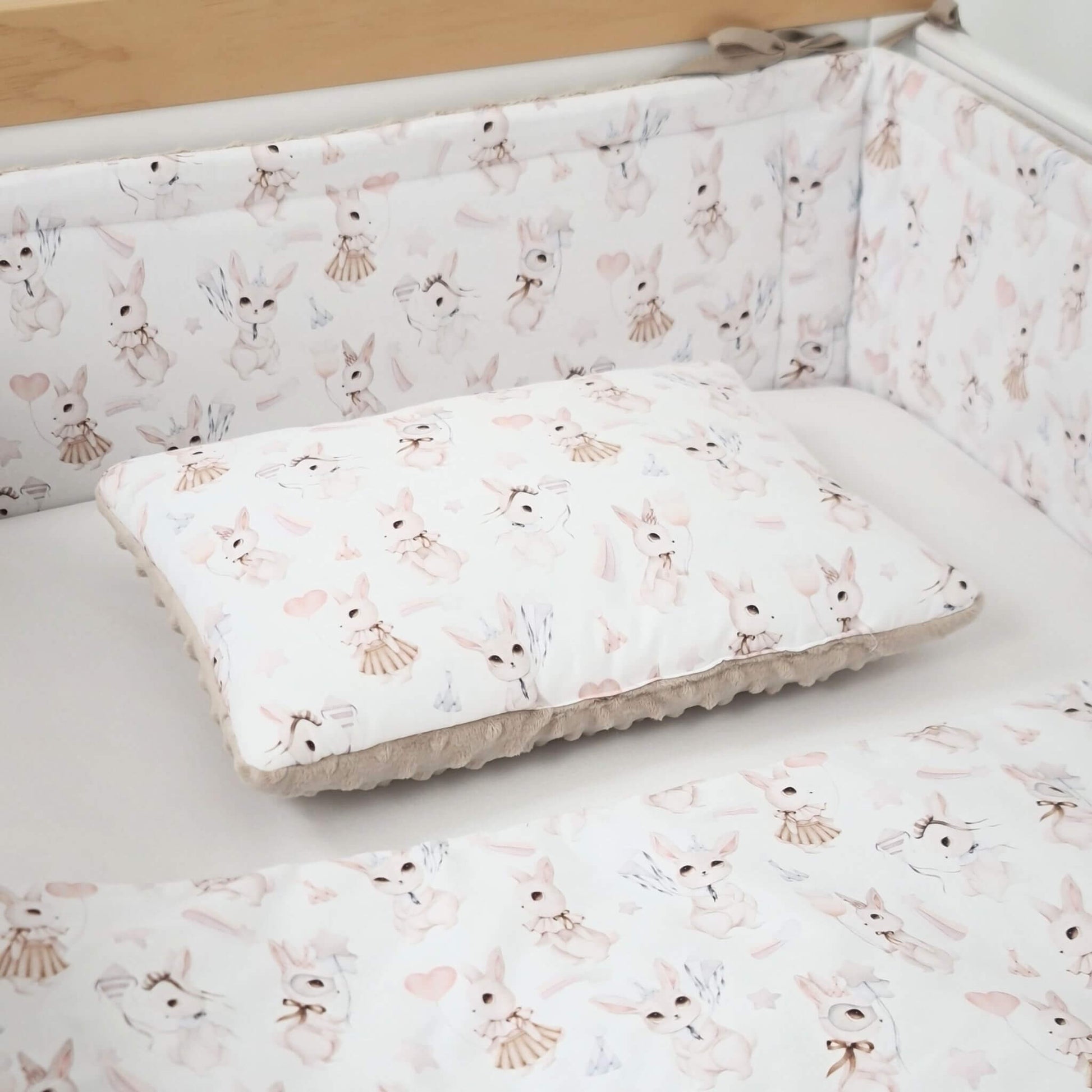 Close-up of retro bunny cotton fabric on cot  bed bumper and baby quilt and pillow in a standard crib