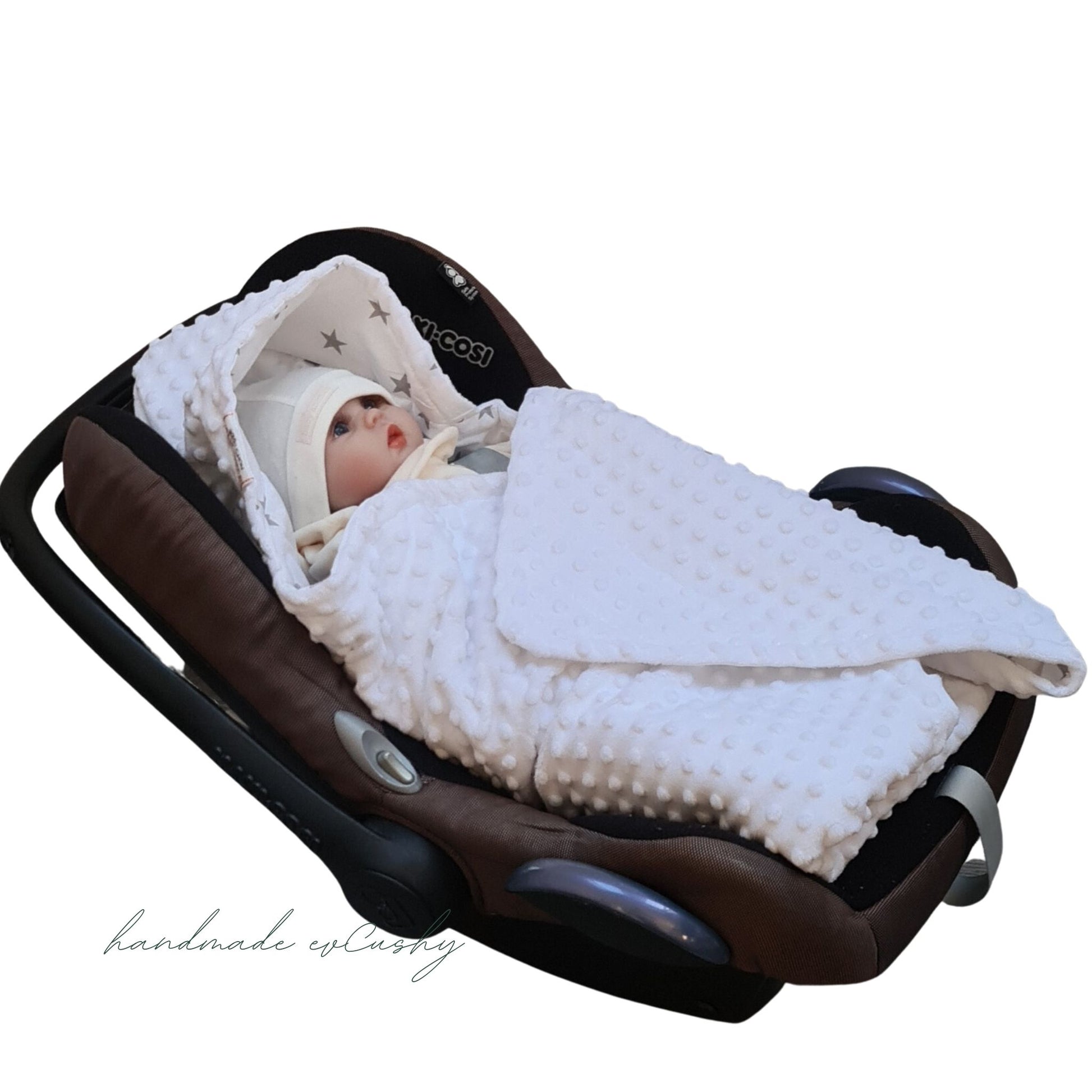 Image: A white car seat blanket with grey stars, featuring a convenient hood for added comfort and warmth. Cosy wrap for a  baby - white.