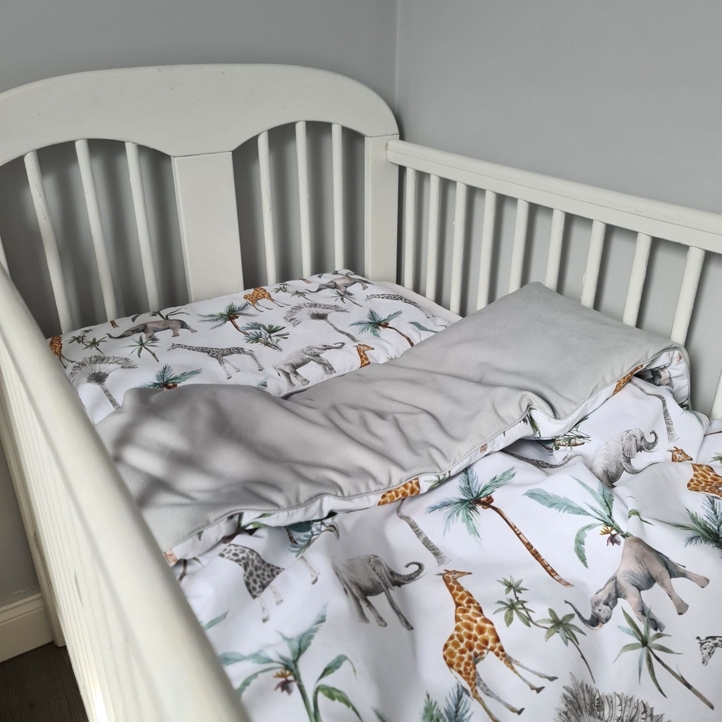 "Image of a charming two-tonal grey and safari-patterned toddler duvet and pillow set, designed to fit perfectly in a cot bed, providing a cozy and adventurous sleep environment."