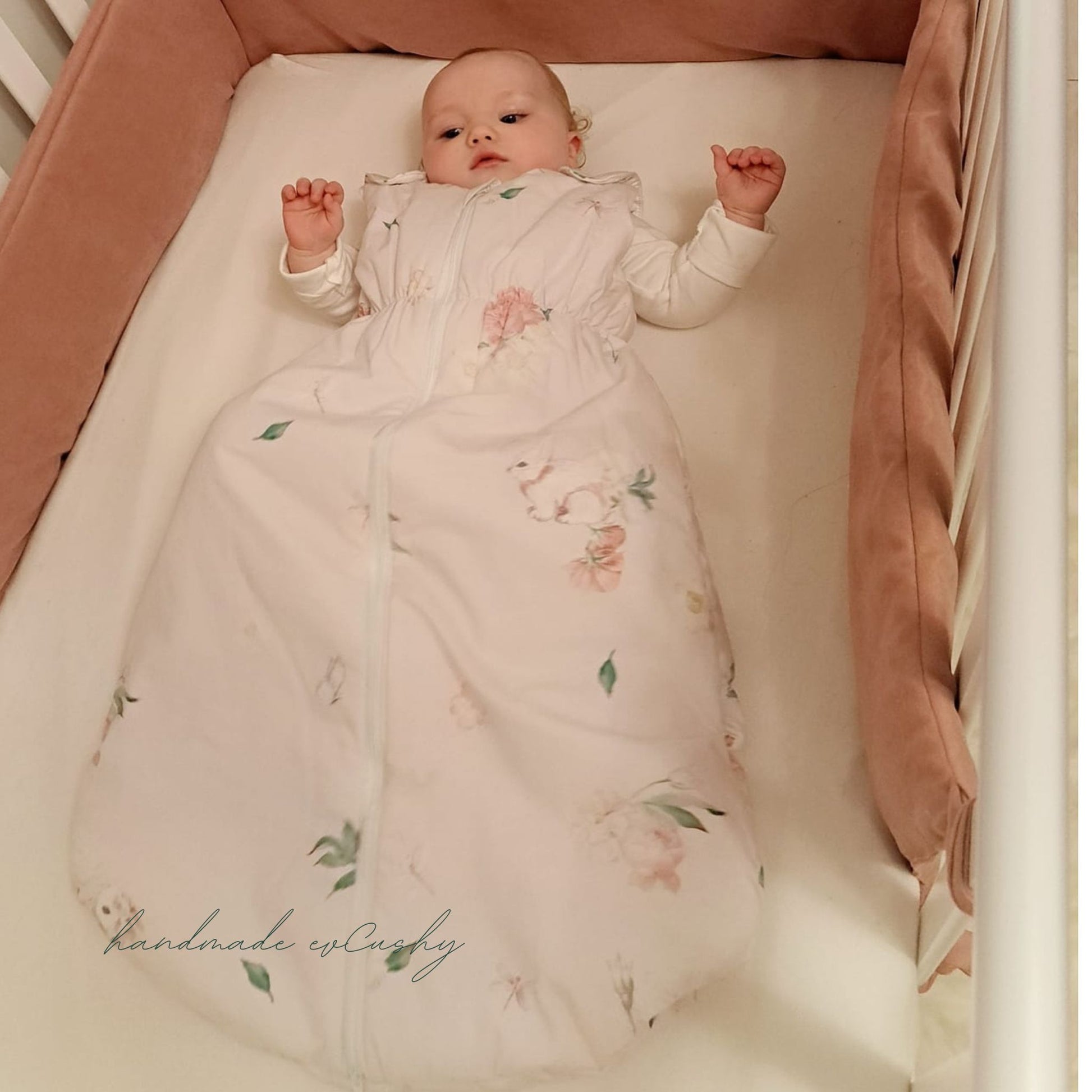 Baby lying in a crib wearing a floral onesie with bunnies pattern